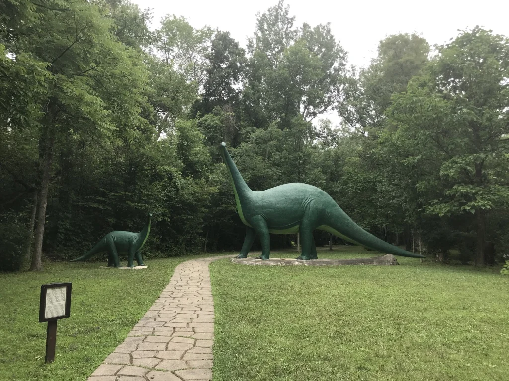 The stone path stretching through the park with Brontosaurus statues on either side