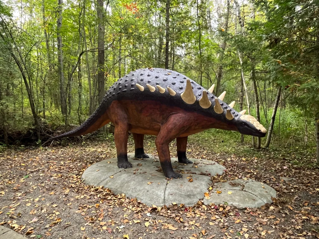 An armoured Ankylosaur statue along the forest path