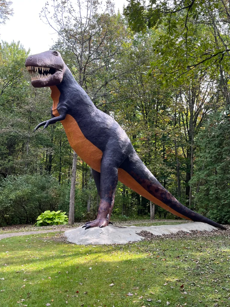 A life-size handcrafted T-Rex statue rising above the treeline