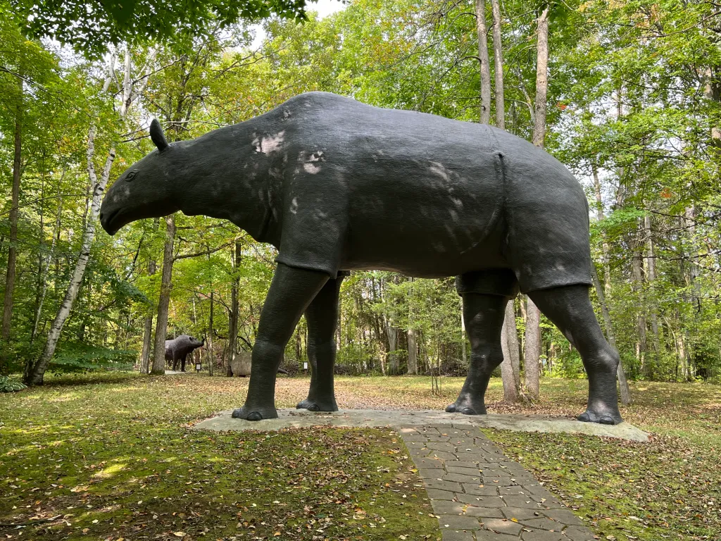 A large prehistoric rhinoceros statue in the woods